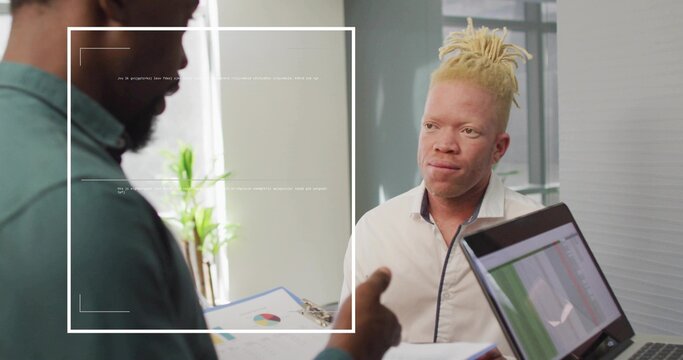 Pointing clipboard with pie chart by teal shirt colleague at desk in office, with laptop graphs - Powered by Adobe