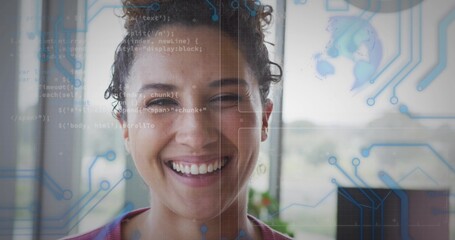 Smiling developer in red top standing before office window, code and circuit graphics floating