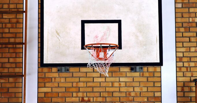 Fototapeta Displaying basketball backboard and rim hanging on brick wall in gym, with net and ladder