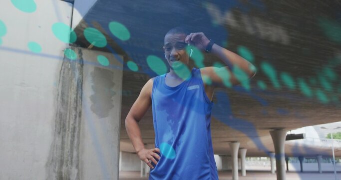 Pausing male athlete wearing earbuds and fitness tracker in underpass, showcasing sweaty sportswear - Powered by Adobe