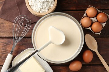 Taking liquid dough from bowl with ladle and ingredients on wooden table, flat lay