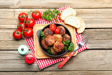 Delicious patties with parsley, tomatoes and bread served on wooden table, flat lay