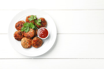 Delicious patties with parsley and ketchup on white wooden table, top view. Space for text
