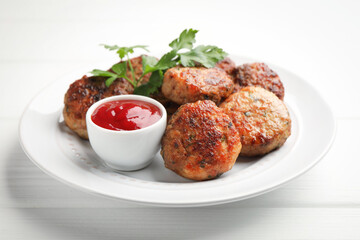 Delicious patties with parsley and ketchup on white wooden table, closeup
