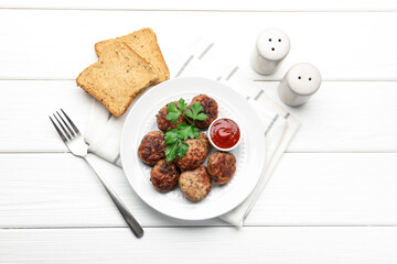 Delicious patties with parsley and ketchup served on white wooden table, flat lay