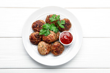 Delicious patties with parsley and ketchup on white wooden table, top view
