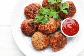 Delicious patties with parsley and ketchup on white wooden table, top view