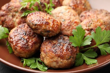Delicious patties with parsley in bowl on table, closeup