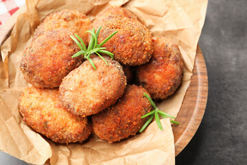Delicious patties with rosemary in bowl on grey textured table, closeup