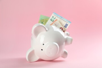 Financial savings. Piggy bank with euro banknotes on pink background