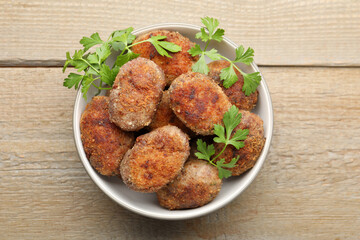 Tasty meat patties with parsley o wooden table, top view