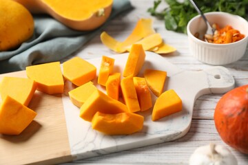 Cut pumpkin, peels, seeds and spices on light wooden table, closeup