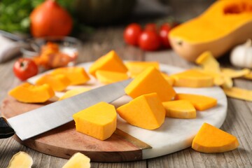 Cut pumpkin, knife and ingredients on wooden table, closeup