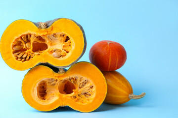 Whole and cut pumpkins on light blue background, closeup with space for text. Gourd family