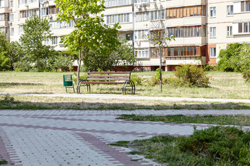 Rest area with bench surrounded by trees and ornamental shrubs in Kyiv, Europe. Place to rest in the city park at summer