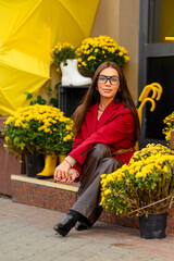 Portrait of a young woman with leaves in an autumn park. A stylish girl in a burgundy jacket strolls outdoors. Autumn fashion.