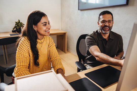 Two architects discussing their project at a computer in a bright office setting