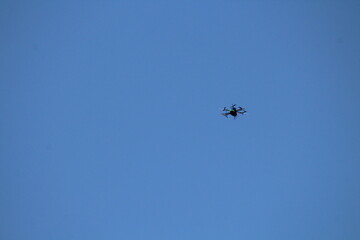 Drone flying on isolated blue sky. Drone frozen in flight on a blue sky background