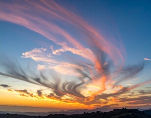 Aerial view of a vibrant sunset with streaked clouds above a mountain ridge