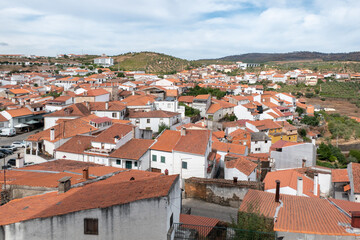Fototapeta premium Vista panorâmica da vila manuelina de Freixo de Espada à Cinta em Trás-os-Montes, rodeada por uma paisagem montanhosa sob um céu parcialmente nublado em Portugal