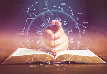 Open book, astrological signs against dark background
