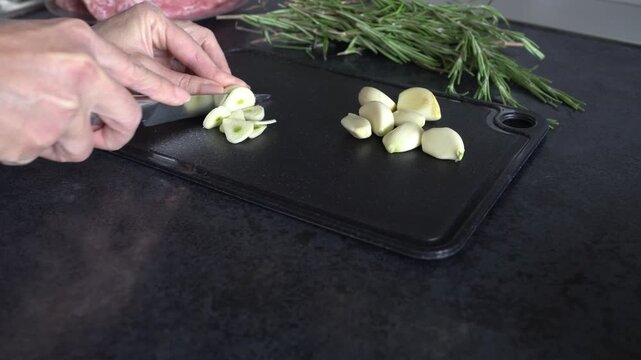 A woman chops garlic on a cutting board. Modern kitchen.
