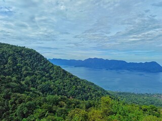 Fototapeta premium Breathtaking Morning View of Lake Maninjau from Puncak Lawang, West Sumatra – Lush Green Hills, Calm Blue Waters, and Distant Mountain Ranges in Indonesia