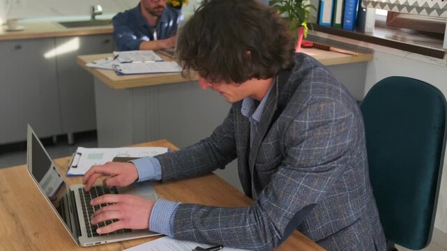 developer working efficiently at desk, software developer concentrating at desk amid collaborative environment, developer engaged in focused work using notes and productivity tools in welllit office