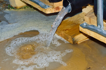 close-up - muddy water pours out of the Eurocube onto the ground and foams