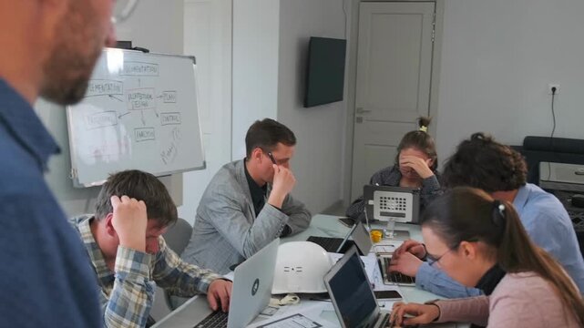Tense office meeting with bald construction manager pointing finger, while young architects look frustrated and stressed. Conflict, mistakes in planning, and workplace pressure in the construction
