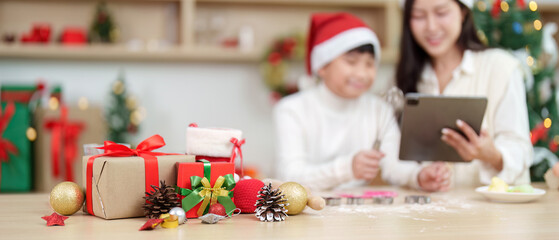 Christmas Gift Planning. A mother and son reviewing recipes on a tablet amidst holiday decorations.