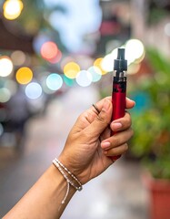 Hand holding a red electronic cigarette with street bokeh in background