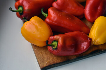 Wet colorful paprika on wooden plate on the table. Harvest of sweet different peppers with water drops.  Healthy organic food concept. Food background.