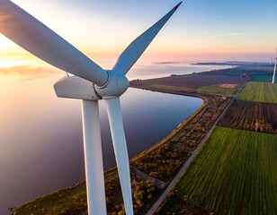 Aerial view of a wind turbine, lake, and fields during sunrise