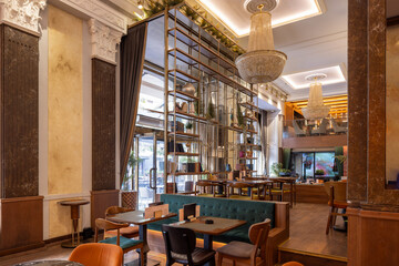 Elegant modern café interior with wooden walls, decorative bookshelves, green velvet seating, warm lighting, and cozy atmosphere