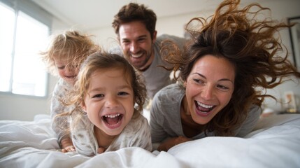 Family laughing and playing together on a bed happy at home