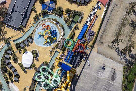 Aerial view of the vibrant aquatic playground with twisting slides and lazy rivers contrasting with the arid landscape, Tynong North, Victoria, Australia.
