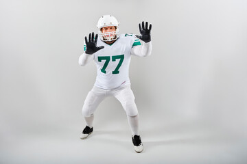American football player in uniform posing in defensive stance indoors