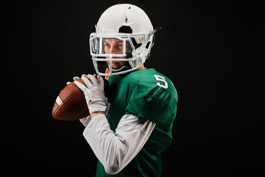 American football player in green jersey holding ball in studio