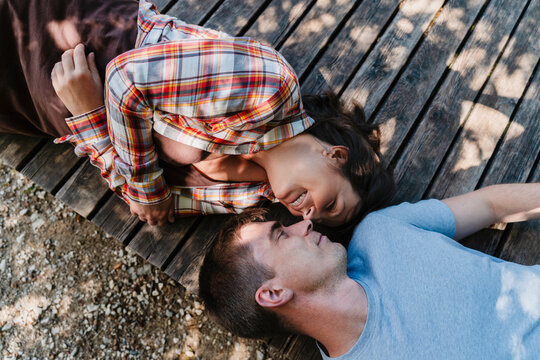Couple laughing together outdoors on wooden deck in sunlight