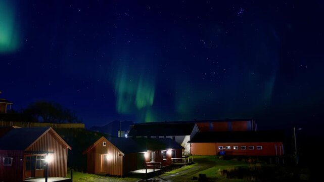 Northern lights over houses and cabins on a snowless autumn night. Lofoten Islands, Northern Norway.