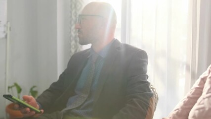 senior executive busy with mobile device, bald executive in suit engaged with his smartphone amidst discussions, balding man in business suit is focused on his mobile device during team meeting - Powered by Adobe