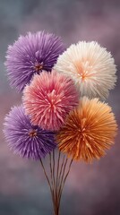 A vibrant long exposure photograph captures a bouquet of colorful fireworks exploding in a dark night sky with subtle pink and grey smoke plumes in the background
