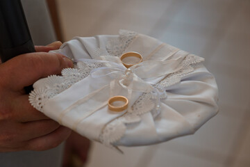 Wedding Rings on White Pillow Ceremony Detail, Gold Bands, Lace Fabric, Blurred Background, Soft Focus, Romantic Celebration, Bridal Accessories.