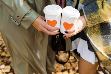Two White Coffee Cups with Orange Hearts Held by People in Autumn, Stylish Trench Coat, Cozy Plaid, Fall Season, Warm Drinks, Lifestyle Photography.