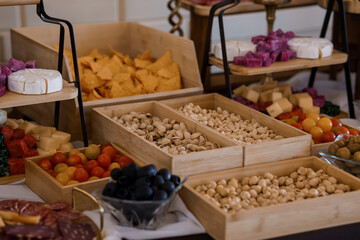 Gourmet Charcuterie Display with Pistachios, Cheeses, Olives, and Nuts Rustic White Wood Table Setting, Food Photography