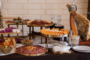 Gourmet Charcuterie Board Display with Prosciutto, Cheeses, Olives, and Large Ham Hock on Dark Table Setting.