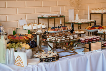 Elegant Dessert Buffet Display with Golden Stands, Fresh Fruit, Pastries and White Tablecloth  Wedding Celebration, Gold Tones.