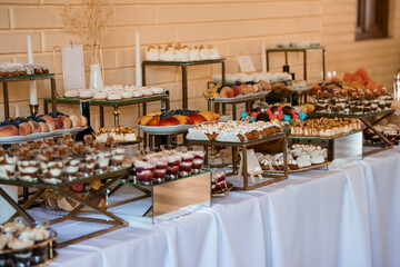 Luxurious Dessert Table Display at Wedding Reception with Gold Accents, White Linens, and Variety of Pastries.