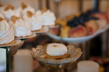 Elegant Dessert Display Featuring White Pavlovas with Gold Accents on Silver Platters, Wedding Cake Table, Soft Focus, Pastel Colors
